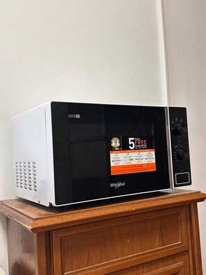 Un microondas blanco sobre un mueble de madera.