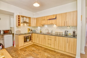 A modern kitchen with wooden cabinets, a built-in oven, a microwave, and a coffee maker. - Lansdowne Lodge - Pass the Keys (Market Rasen)