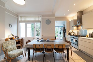 Une cuisine moderne avec un coin repas, dotée d’une grande fenêtre, d’une horloge et offrant une vue sur l’extérieur.