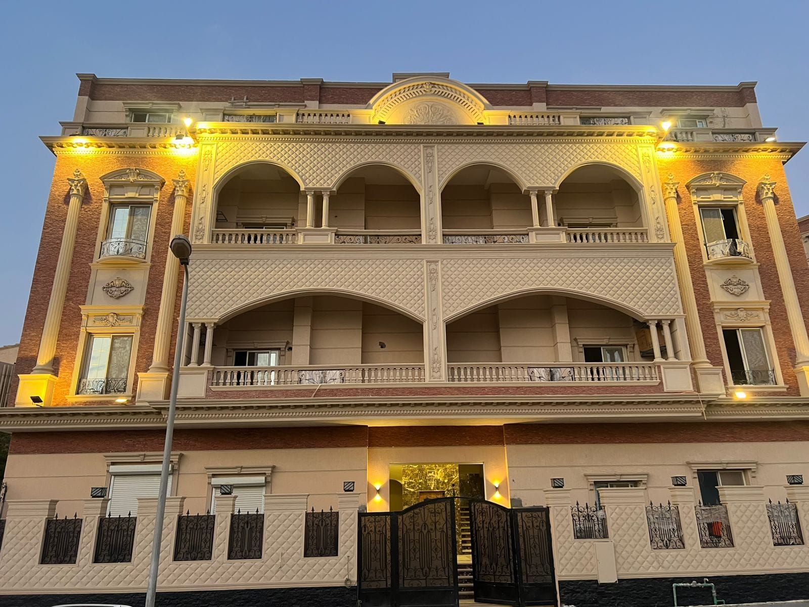 A multi-story building with a symmetrical facade, large arched windows, and a central entrance with a staircase.