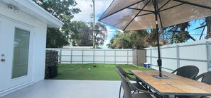 A patio with a table and chairs, a covered umbrella, and a fenced backyard. - Pool Home w/ 2 Kings near Beach, FLL & Hard Rock (Hollywood)