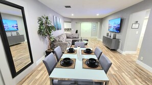A modern dining area with a white table set for four, surrounded by grey chairs. - Pool Home w/ 2 Kings near Beach, FLL & Hard Rock (Hollywood)