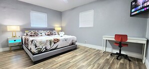 A bedroom with a bed, bedside tables, a desk, and a chair. - Pool Home w/ 2 Kings near Beach, FLL & Hard Rock (Hollywood)