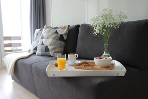 A breakfast tray on a sofa with a glass of orange juice, a cup of coffee, a bowl of yogurt with berries, and a vase of flowers. - New Listing (Davos Platz)