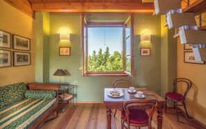 Une pièce comprenant un lit, une table avec une assiette de nourriture, des chaises, une lampe et des tableaux encadrés accrochés au mur.