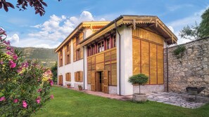 Un bâtiment traditionnel en bois, doté d’un mur en pierre, d’un petit jardin et offrant une vue sur les montagnes.