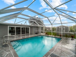 A swimming pool with a glass ceiling structure, surrounded by stone tiles. - Amazing home in the heart of port charlotte with beautiful water front views (Port Charlotte)
