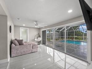Ein modernes Wohnzimmer mit einem großen Glasfenster, das in einen Poolbereich führt.