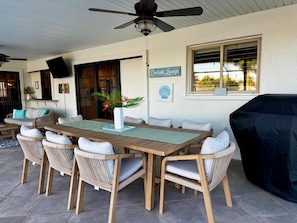 An outdoor patio with a wooden table and wicker chairs, a ceiling fan, and a sign reading 'Dooseide Lounge'. - Villa 29 NEW to rental by Sue Larson Rentals! Gulf Access (cape coral)