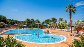 A swimming pool area with multiple pools, sun loungers, and palm trees. - Mobile Home 'Camping Le Clos Du Thym' with Shared Pool, Wi-Fi and Air Conditioning (Argelès-sur-Mer)