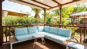 A wooden deck with a light blue sectional sofa and a small round table.