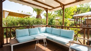 A wooden deck with a light blue sectional sofa and a small round table. - Mobile Home 'Camping Le Clos Du Thym' with Shared Pool, Wi-Fi and Air Conditioning (Argelès-sur-Mer)