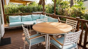 A wooden deck with a round table and chairs, a light blue sofa, and a white railing. - Mobile Home 'Camping Le Clos Du Thym' with Shared Pool, Wi-Fi and Air Conditioning (Argelès-sur-Mer)