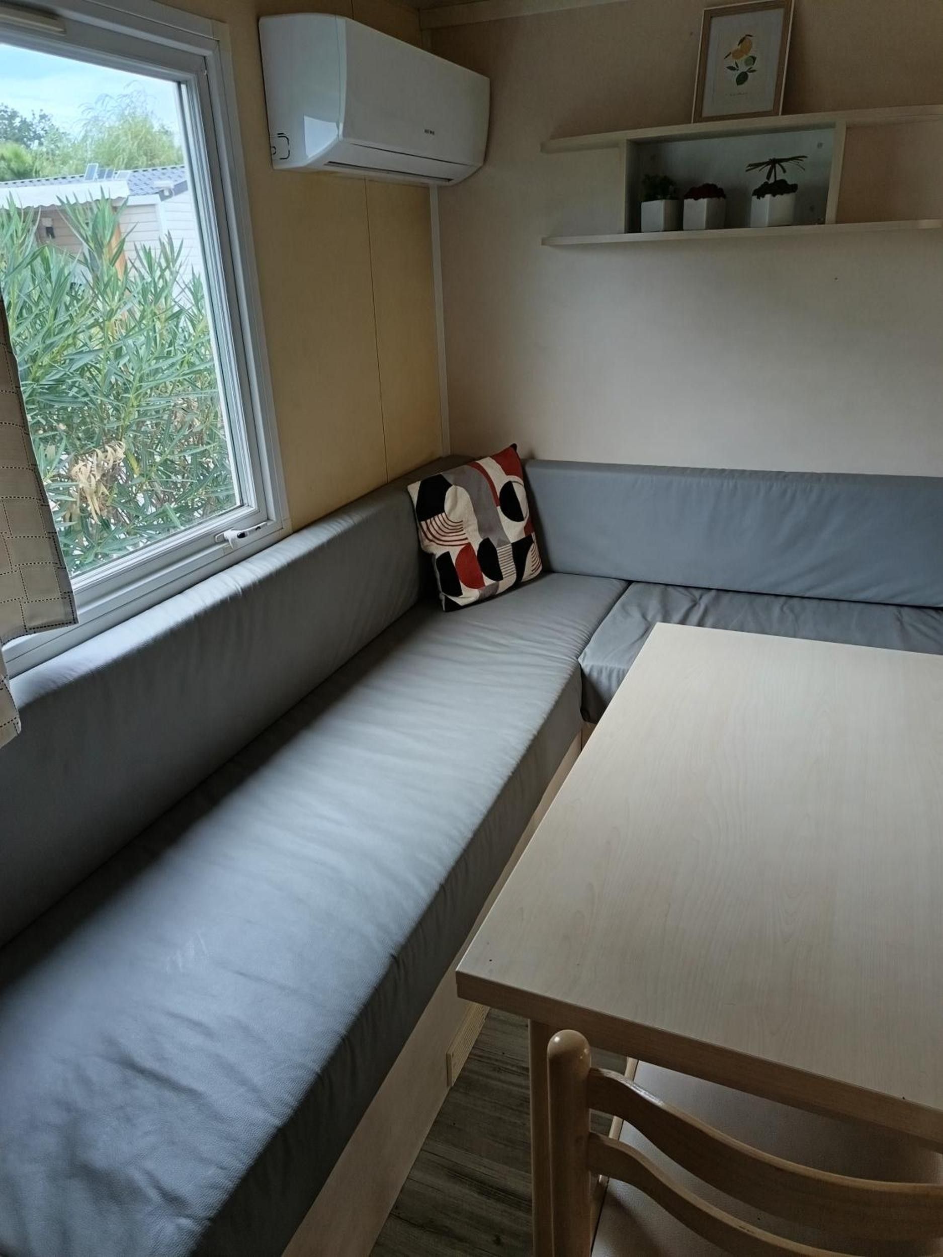 Ein Zimmer mit eingebautem Sitzplatz, einem Tisch und einem Fenster.
