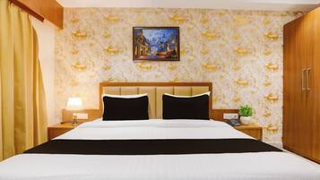 Ein Hotelzimmer mit Bett, Nachttisch, Lampe, einem Bild an der Wand und einem Blumentopf.
