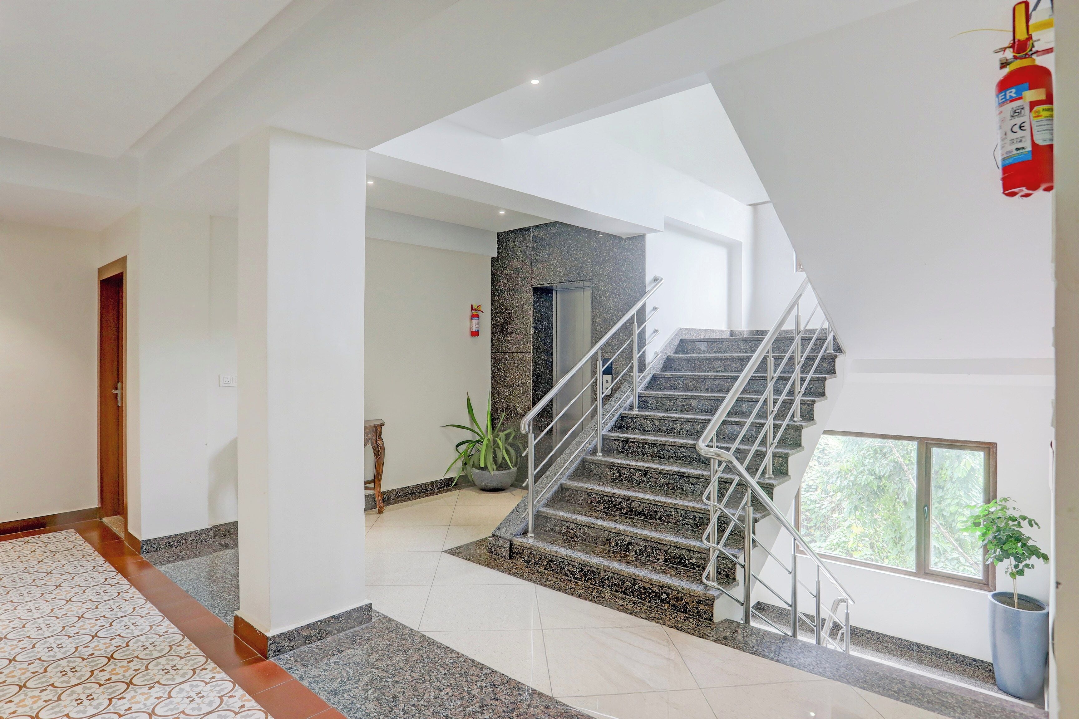 A modern interior with a staircase, a fire extinguisher, and a potted plant.