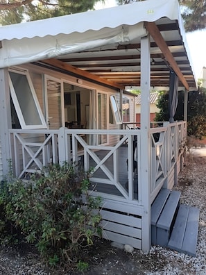 A covered outdoor area with a wooden deck, a white railing, and a small porch. - Mobile Home 'Avec Piscine' with Shared Pool, Wi-Fi and Air Conditioning (Argelès-sur-Mer)