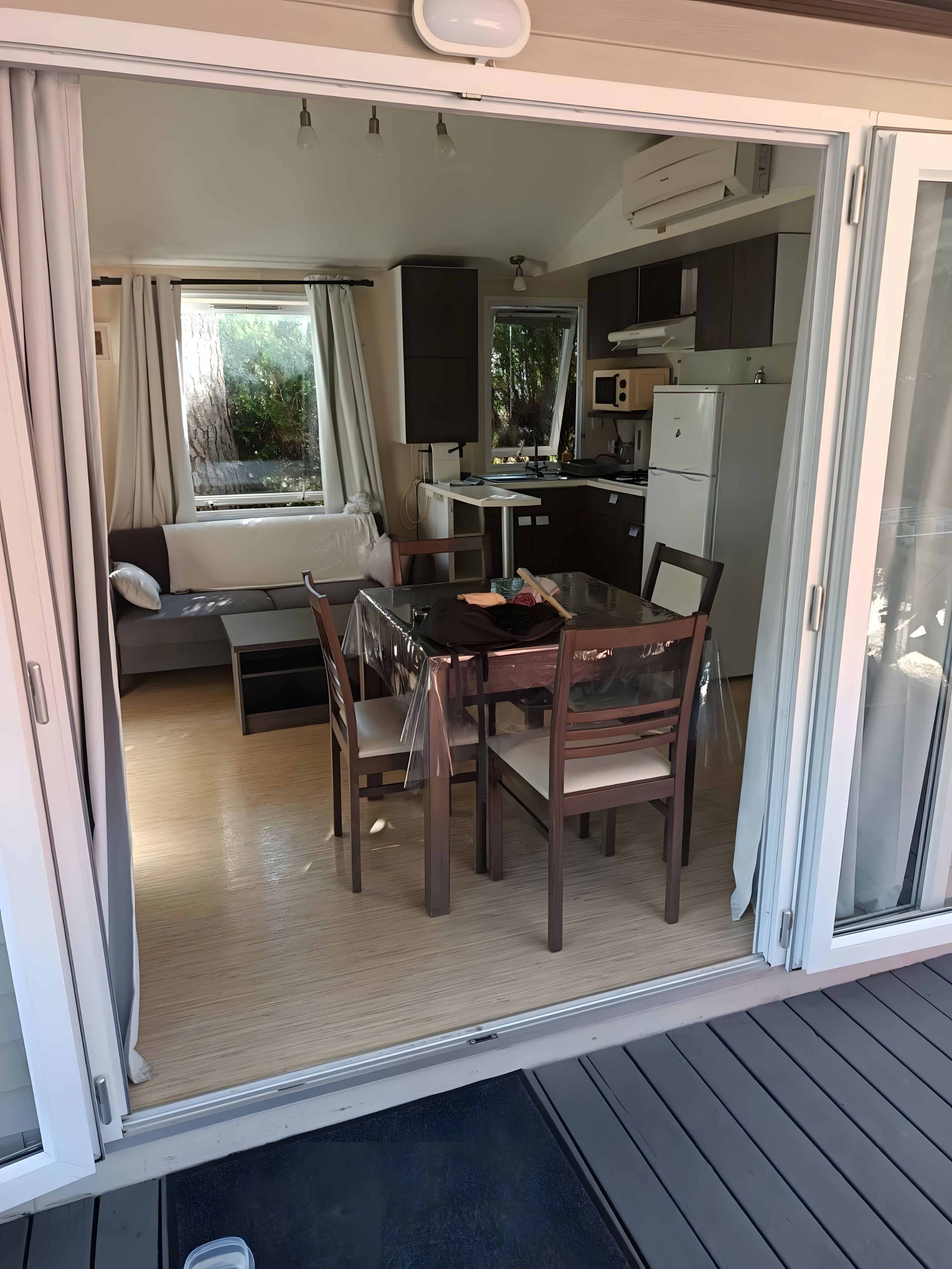 A compact living space with a kitchenette, a dining area, and a sofa near a window.