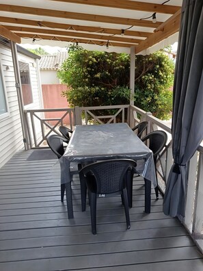 Um alpendre coberto com mesa e cadeiras, teto de madeira e vista para o verde.