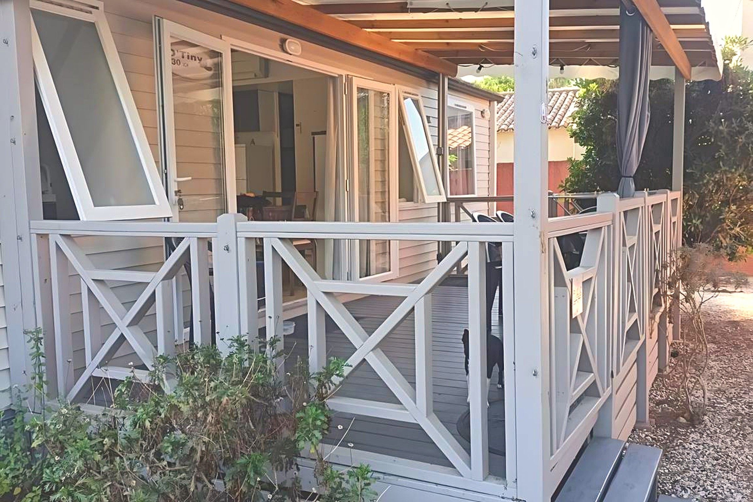 A covered outdoor area with a wooden deck and white railings.