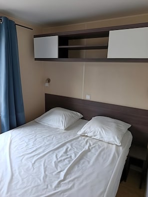 A bed with white linens, a headboard, and a bedside table. - Mobile Home 'Avec Piscine' with Shared Pool, Wi-Fi and Air Conditioning (Argelès-sur-Mer)