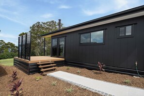 Een modern gebouw met een plat dak, grote ramen en een houten terras.
