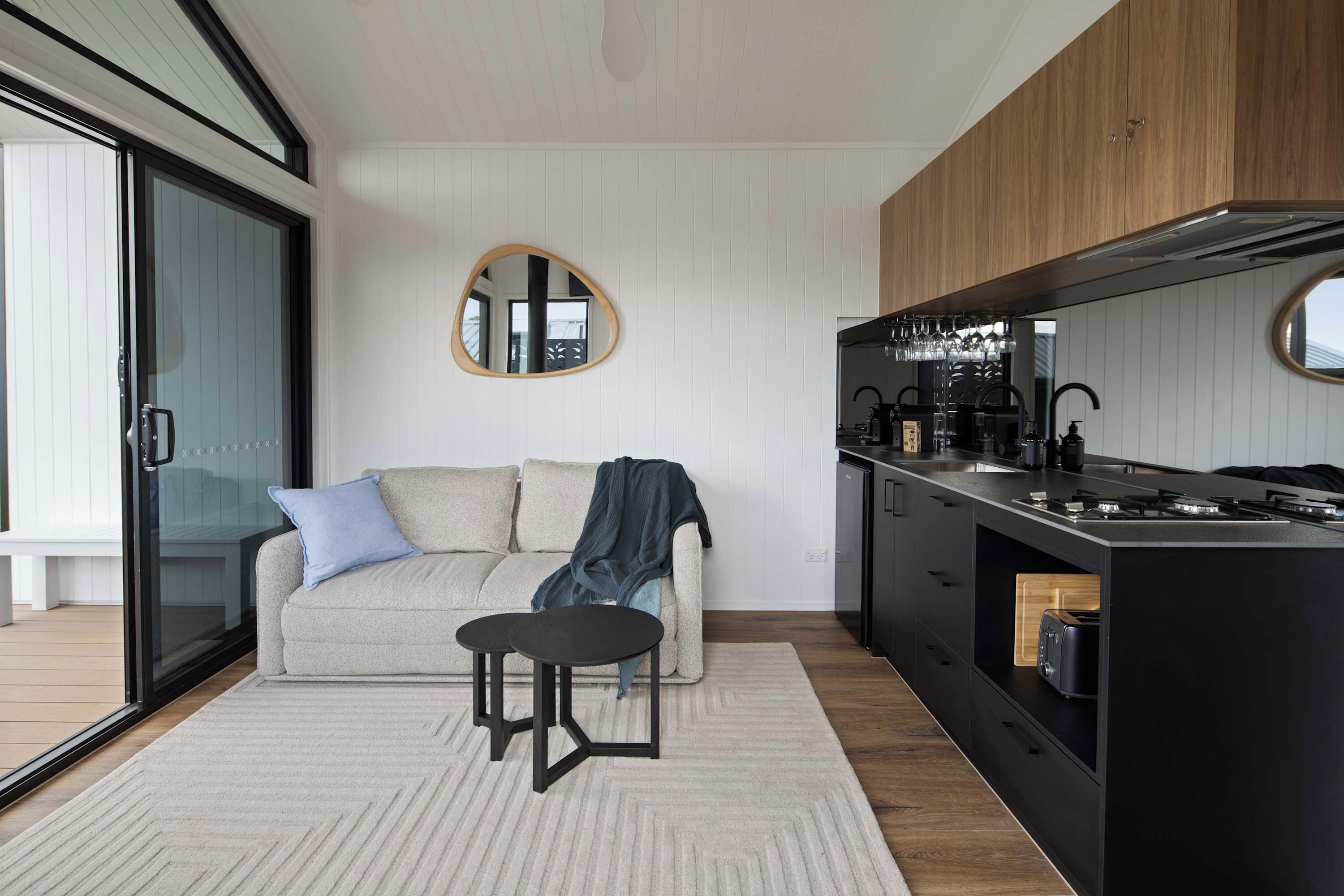 Une cuisine moderne dotée d’un îlot central intégré, de meubles de rangement noirs et d’un miroir rond accroché au mur.
