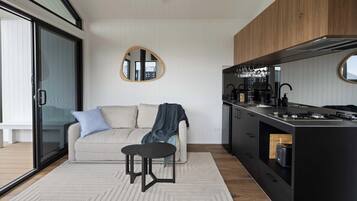 Une cuisine moderne dotée d’un îlot central intégré, de meubles de rangement noirs et d’un miroir rond accroché au mur.
