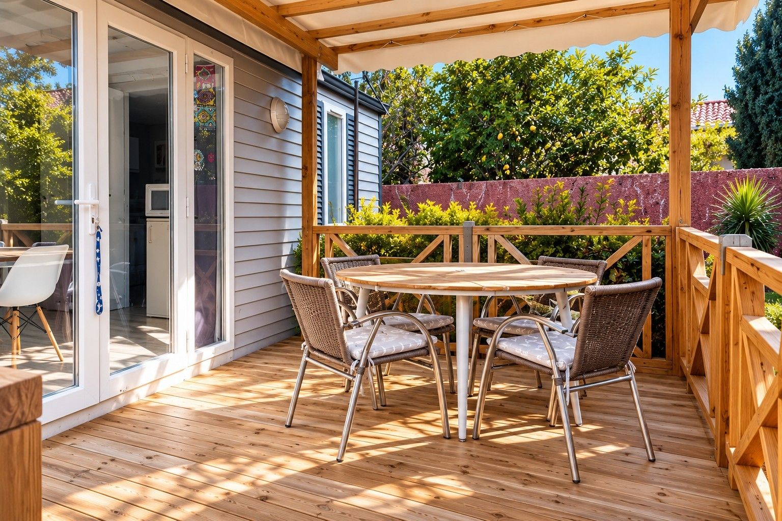 Un terrazzo in legno con tavolo e sedie, una porta scorrevole in vetro e vista sul verde.