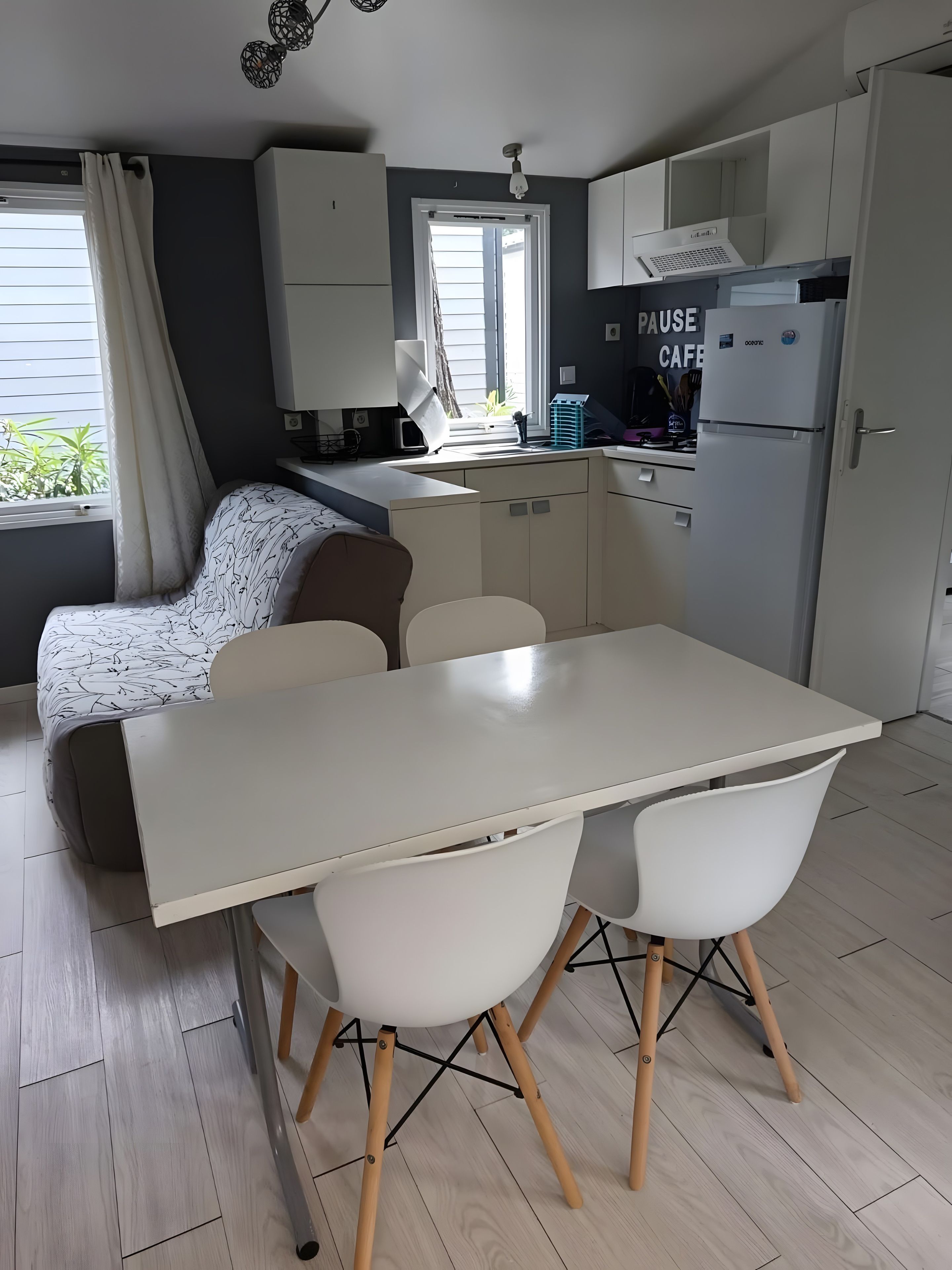 Cocina compacta con comedor, sofá y ventana con cortinas.
