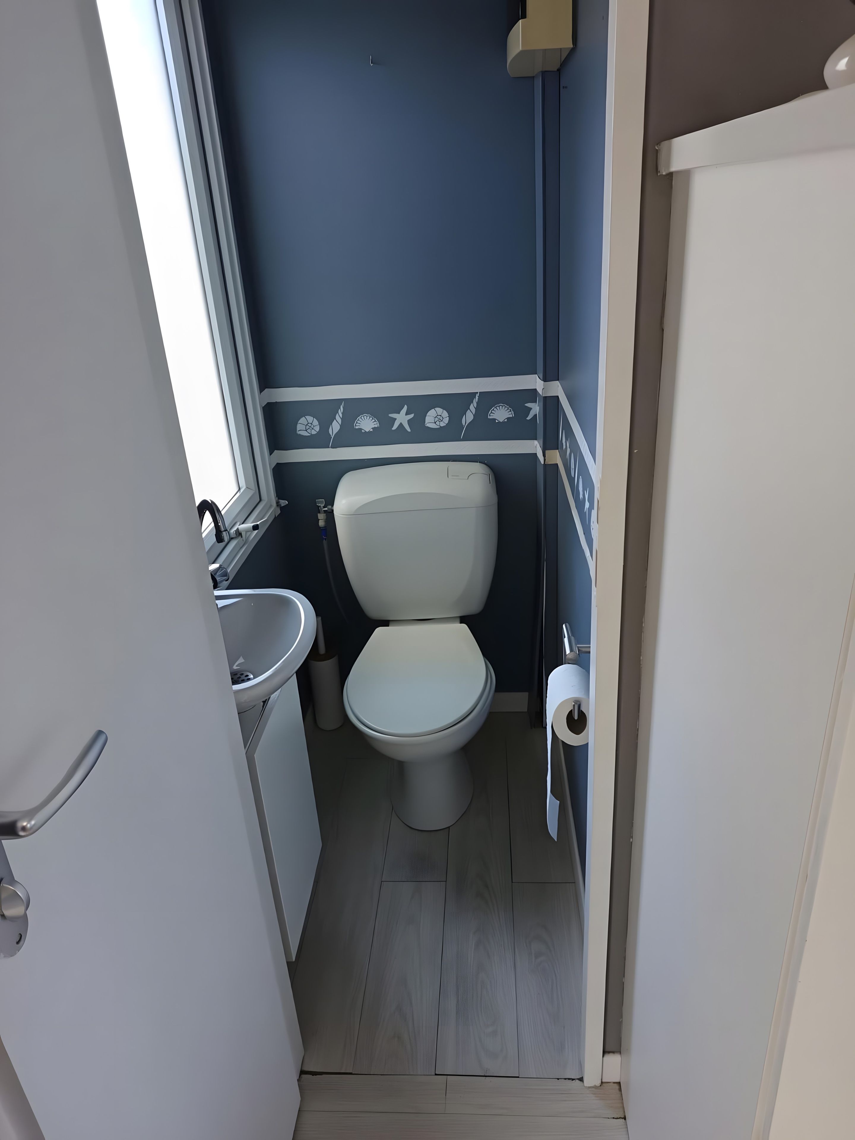 A compact bathroom with a toilet, sink, and a window.