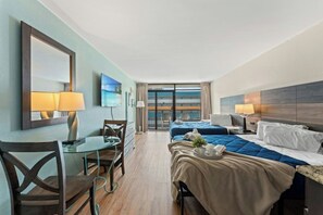 Een hotelkamer met een bed, een bureau, een stoel, een televisie en een balkon met uitzicht.