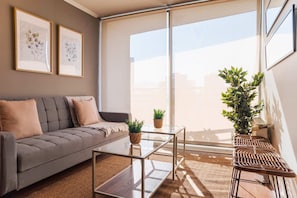 A modern living room with a grey sofa, a glass coffee table, and a large window. - Chic Providencia Apt Cozy Stay Ideal for 3 Guests (Providencia)