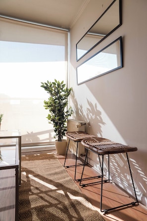 A sunlit room with a large window, a potted plant, a radiator, and two wicker chairs. - Chic Providencia Apt Cozy Stay Ideal for 3 Guests (Providencia)