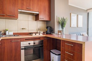 Eine moderne Küche mit Holzausbau, einem Edelstahlherd und einem Mülleimer.