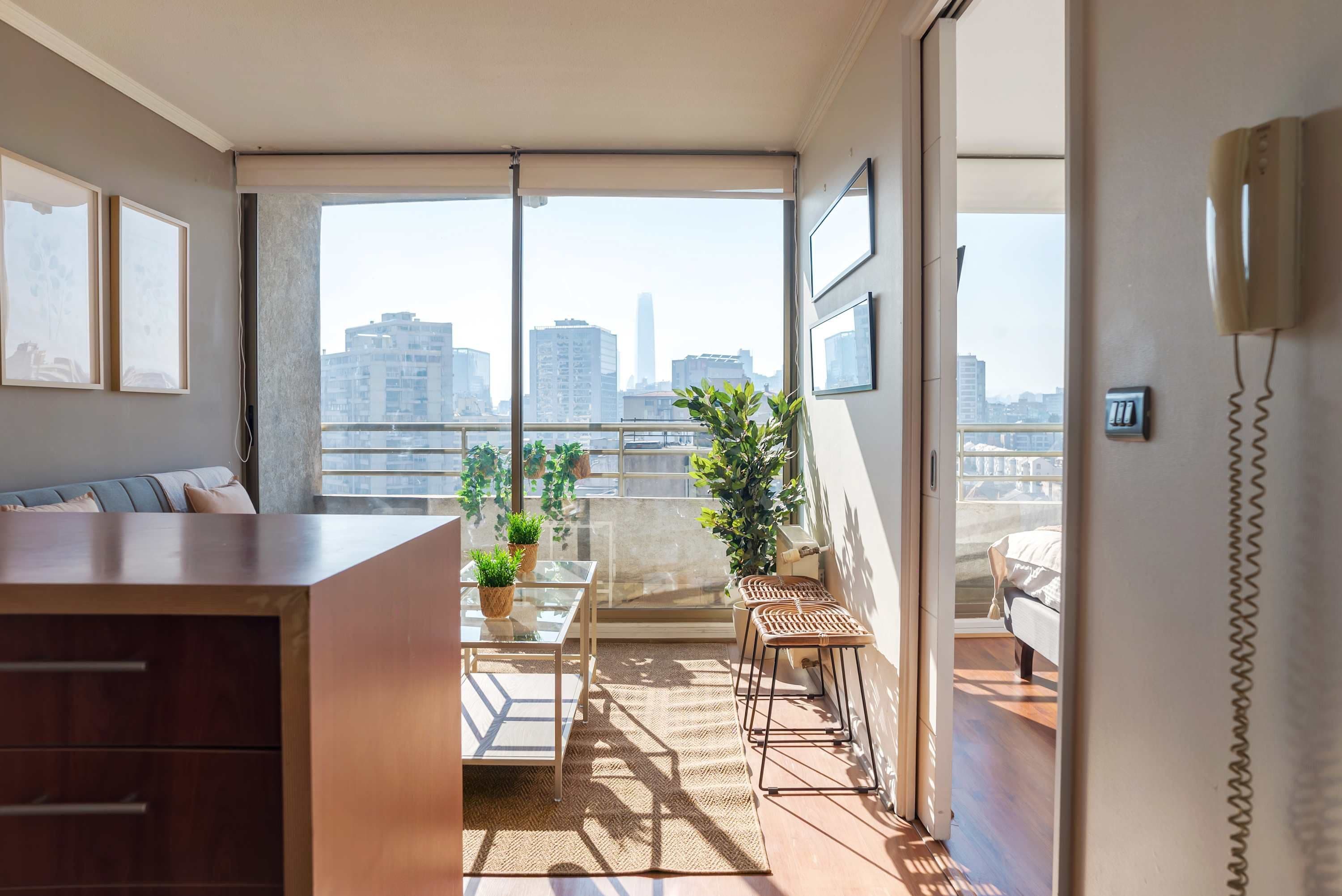 A modern apartment with a balcony, a dining area, and a view of the city skyline.