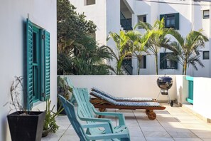 A terrace with two lounge chairs, a barbecue grill, and potted plants. - Santorini Ballito | 180º Sea Views, Braai and Pool (Cape Town)