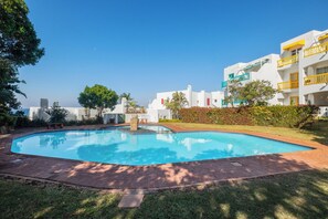 A swimming pool surrounded by a brick patio, with white buildings and balconies in the background. - Santorini Ballito | 180º Sea Views, Braai and Pool (Cape Town)