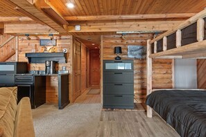 Un acogedor interior de cabaña con kitchenette, una cama y un área de escritorio.