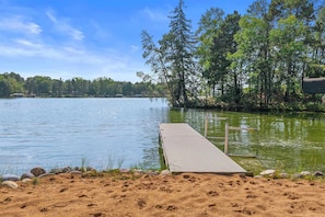 A sandy beach with a wooden dock extending into a lake, surrounded by trees. - Escape to a cozy log cabin to enjoy golf, lake days, and winter adventures. (Nekoosa)