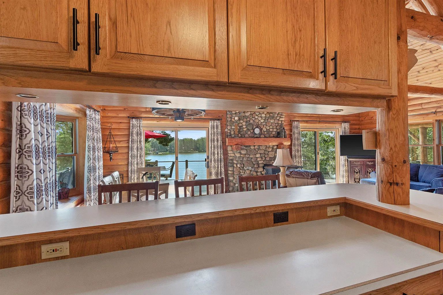 L’intérieur d’un chalet en bois comprend un coin cuisine, un espace repas et une cheminée en pierre.