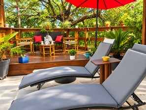 A wooden deck with lounge chairs, a table, and potted plants.