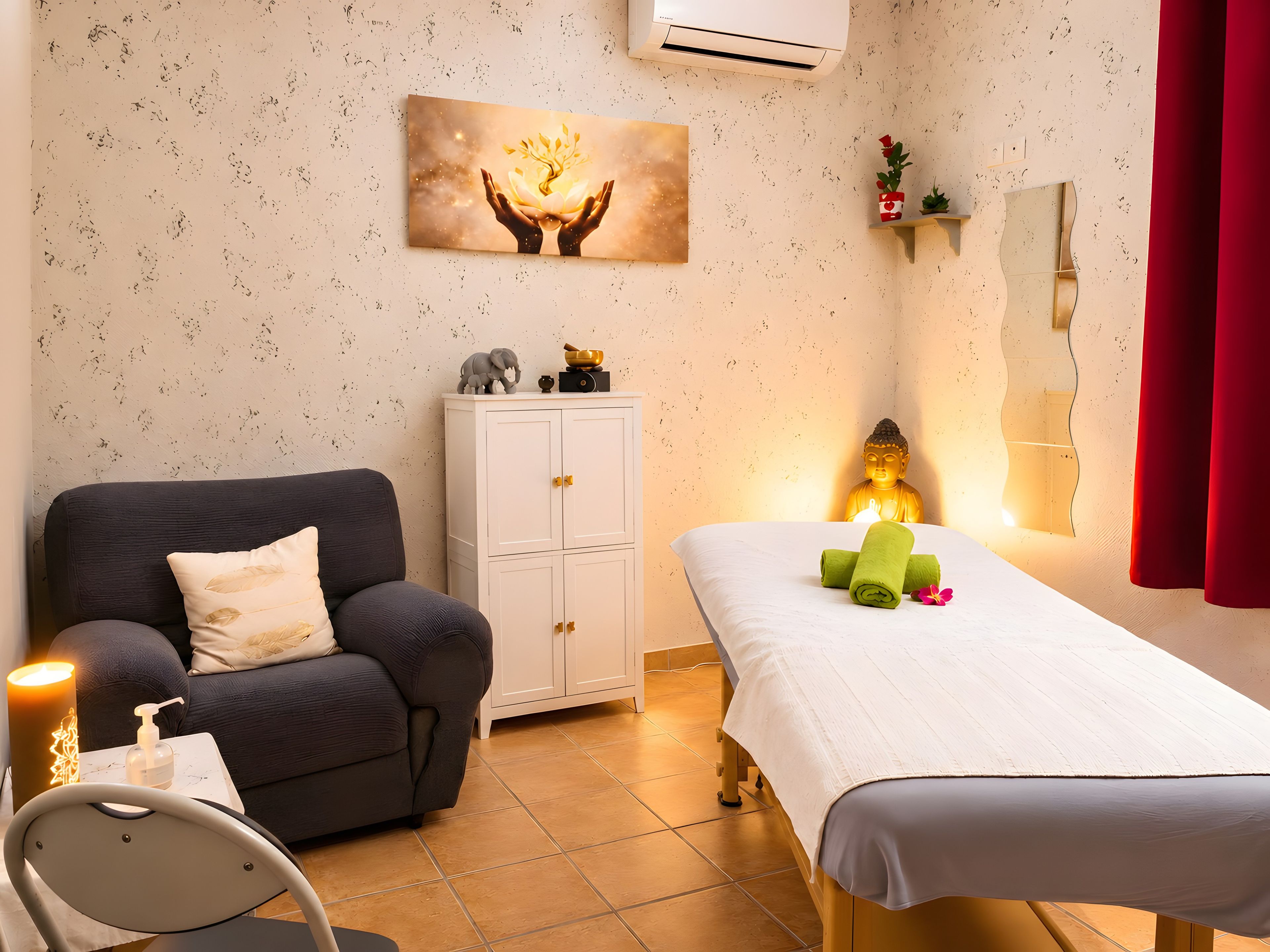 Une pièce comprenant une table de massage, un canapé, une armoire, une statue de Bouddha et un climatiseur fixé au mur.