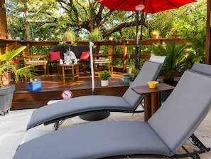 Un espace patio aménagé avec des chaises longues, une table et des plantes en pot.