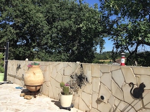 Un mur de pierres sur lequel est sculptée une représentation de papillon, un grand pot en argile et une plante en pot.