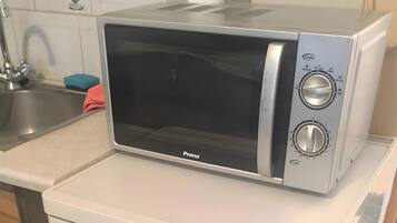 Eine kompakte Küche mit Geschirrspüler von Bosch, einer Mikrowelle und einem kleinen Kühlschrank.