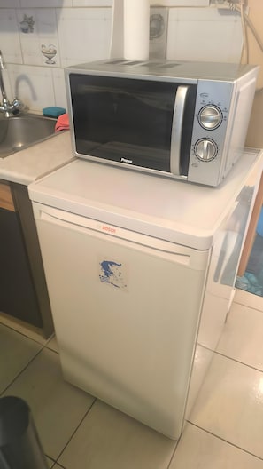 Eine kompakte Küche mit Geschirrspüler von Bosch, einer Mikrowelle und einem kleinen Kühlschrank.