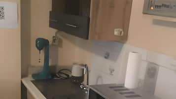 Une cuisine compacte équipée d’un four à micro-ondes, d’une machine à café et d’un lave-linge.