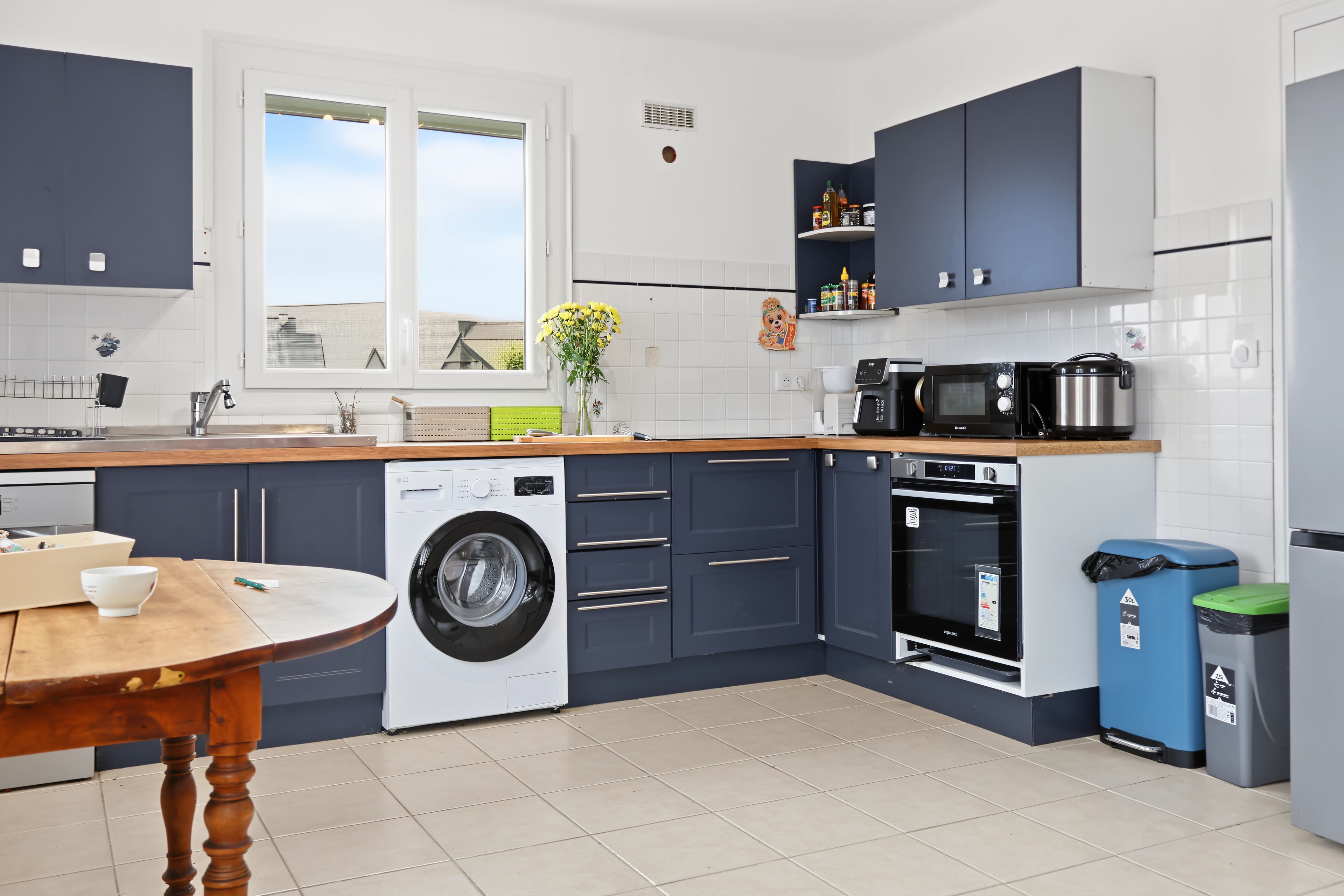 A modern kitchen with a washing machine, microwave, oven, and a sink.