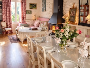 A dining area with a table set for four, a fireplace, and a cozy seating area with a sofa and a chair.